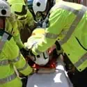 Casualty being placed on a stretcher and being supported by rescue crews in PPE