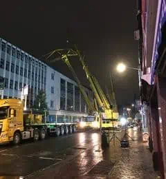 Crane on road over large building at night