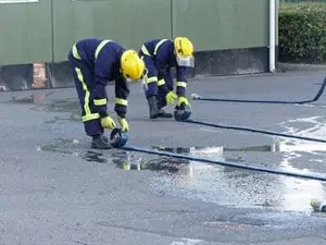 two young firefighters rolling out hoses