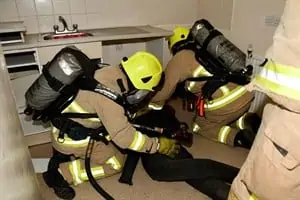 Firefighters wearing breathing apparatus inside a kitchen