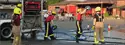 A group of fire cadets working with the hose while beside an engine.