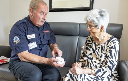 A Safe and Well technician demonstrating how to test a smoke alarm by pressing the test button.