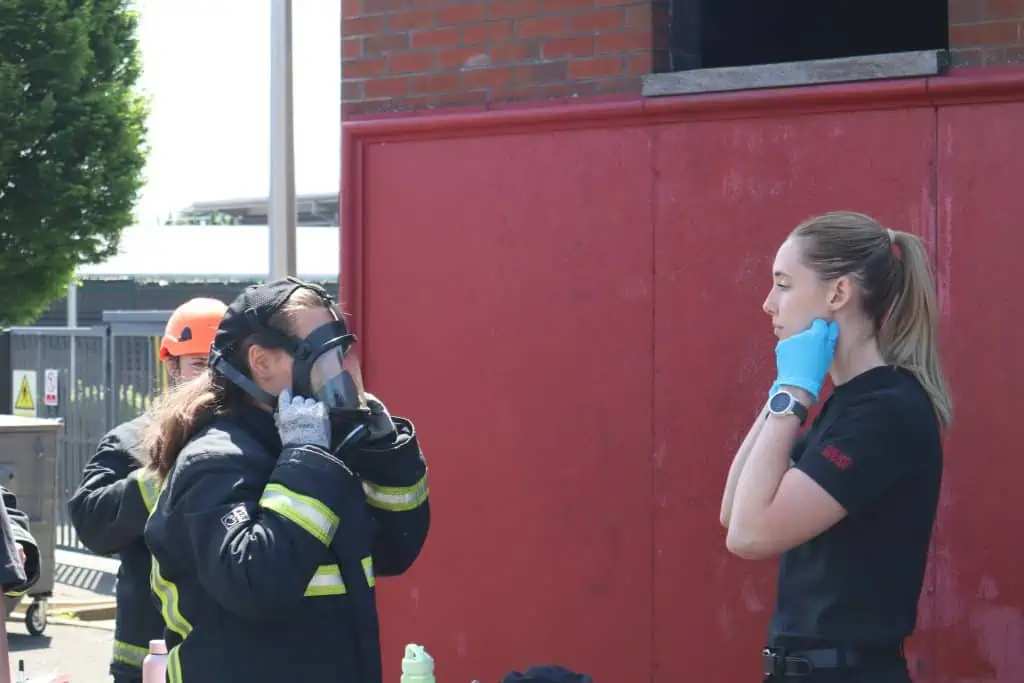 A firefighter shows attendees how to wear a breathing apparatus mask