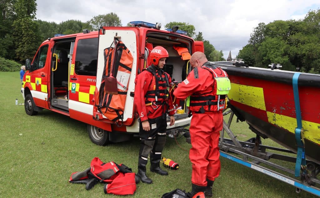 two firefighters putting on water rescue gear.