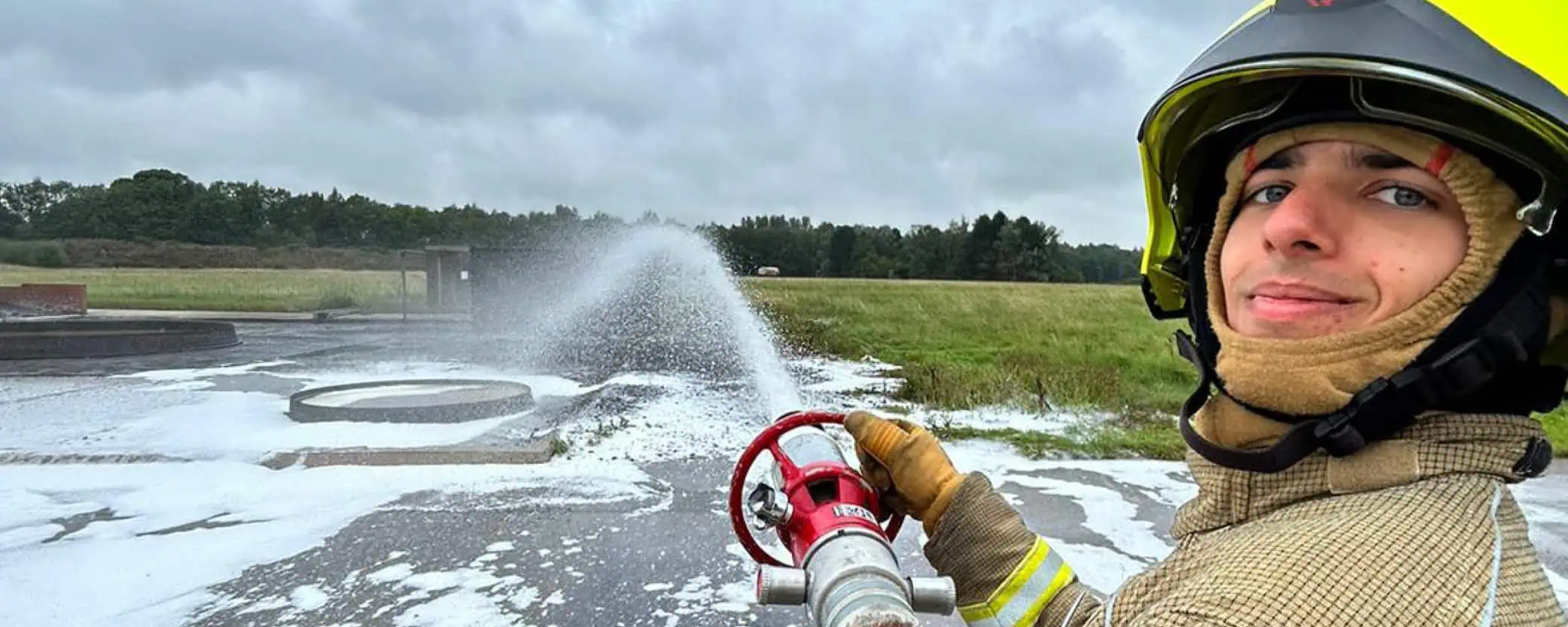 Firefighter spraying water through a hose reel
