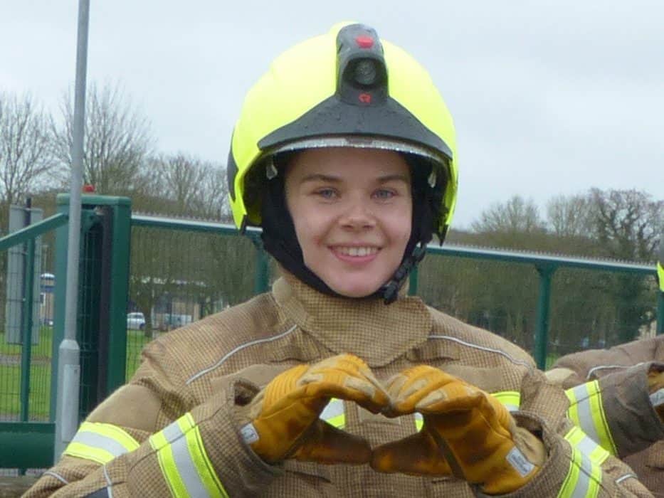 A firefighter in full gear making a heart shape with hands at Royal Berkshire Fire and Rescue Servic.
