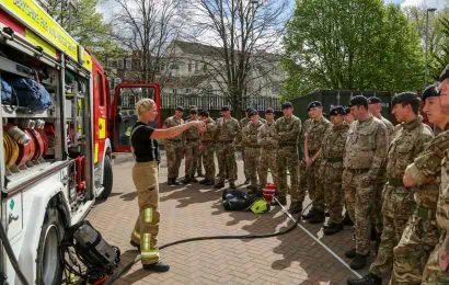 A firefighter talking with several soldiers.
