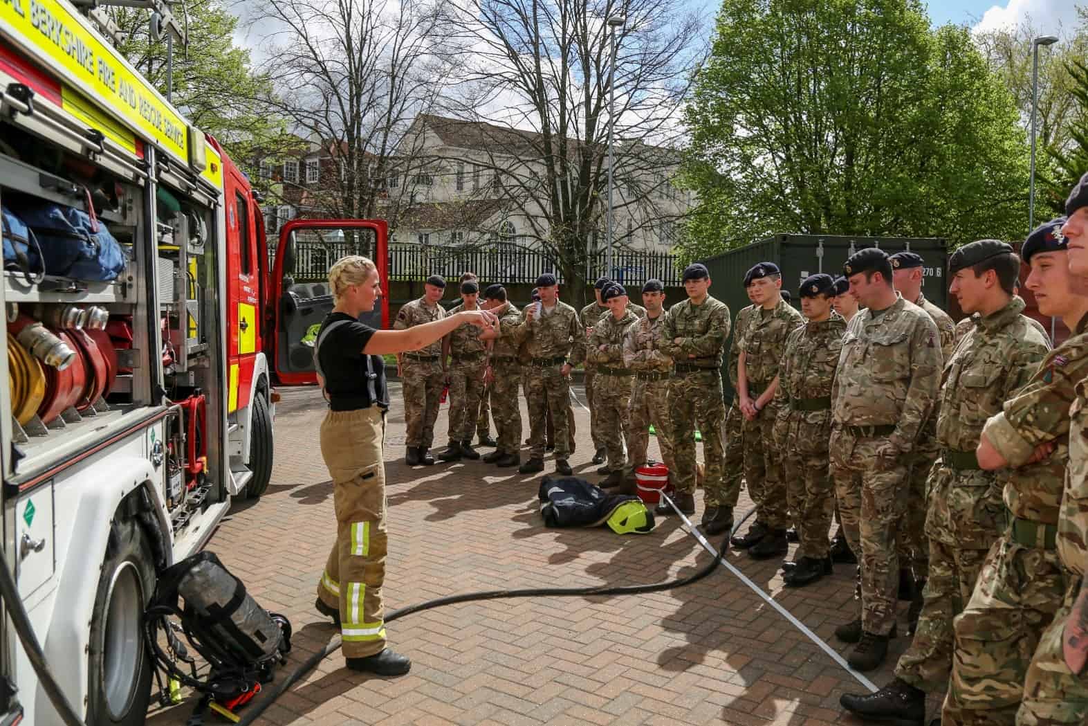 A firefighter talking with several soldiers.