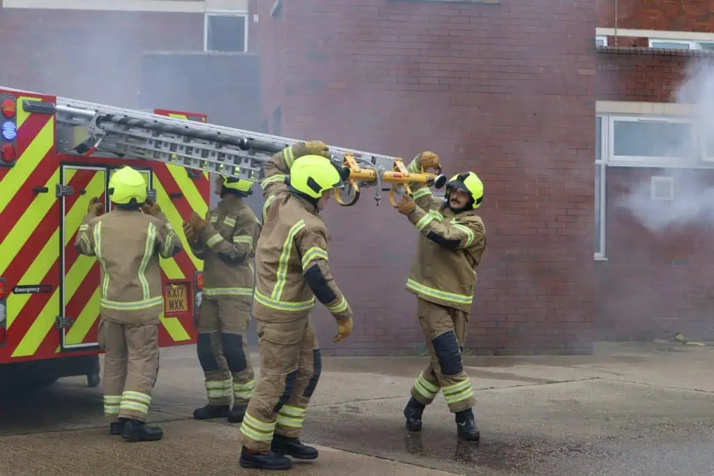 Firefighters unloading a ladder from the fire engine