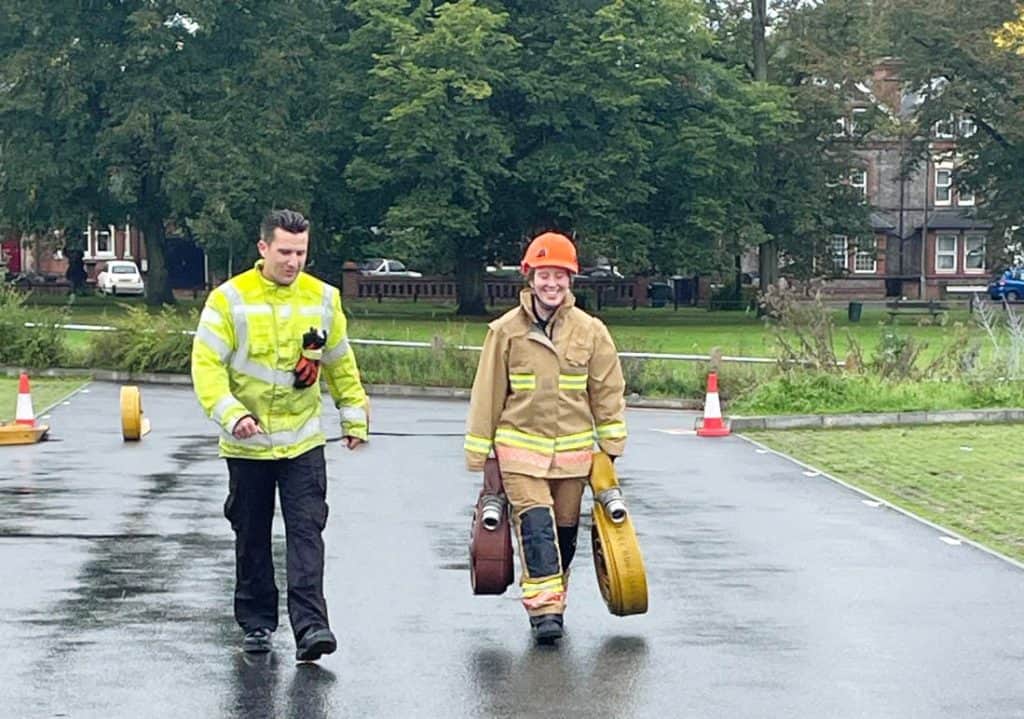 Emergency firefighters walking on wet road with safety equipment in a park area, Royal Berkshire Fir.