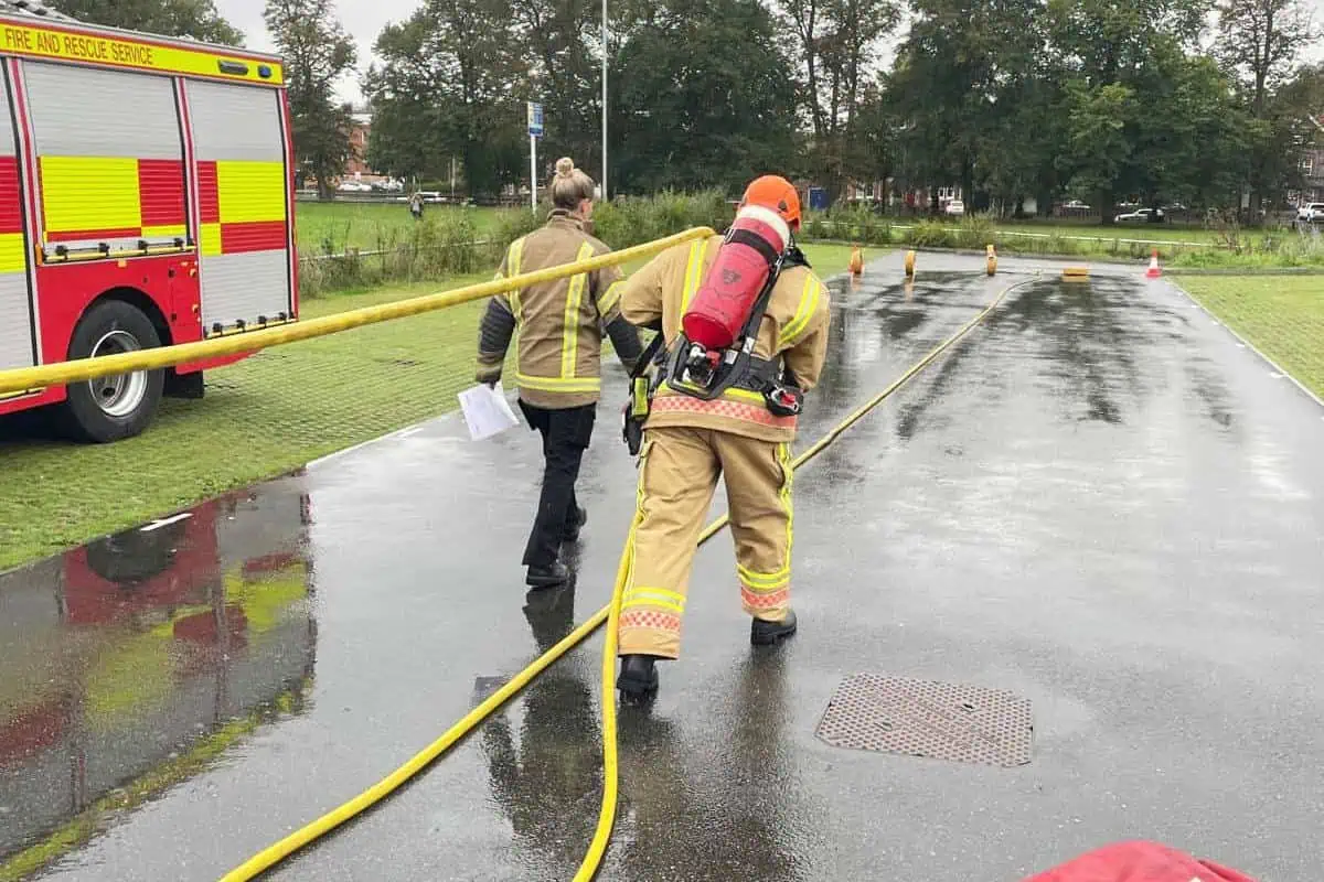 A firefighter showing someone how to do a drill ground assessment.