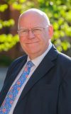 Councillor Jeff Brooks, Chair of Royal Berkshire Fire Authority standing in front of a green background.