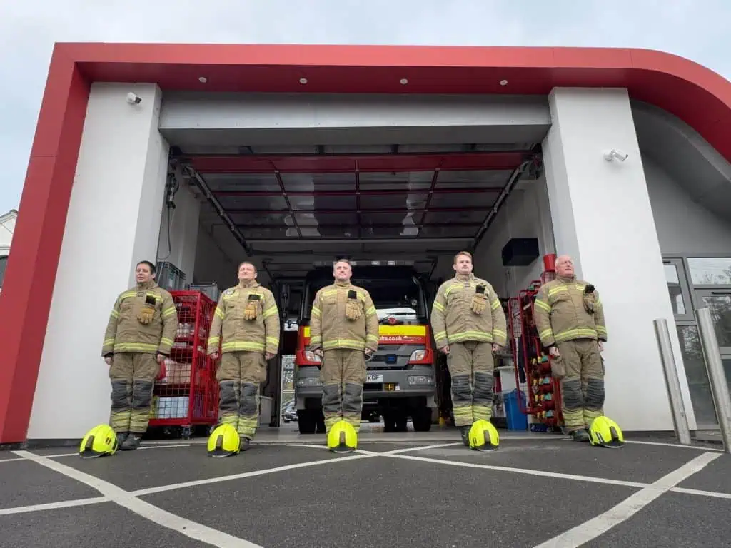 Five firefighters with their helmets on the ground in front of them at Hungerford Fire Station.