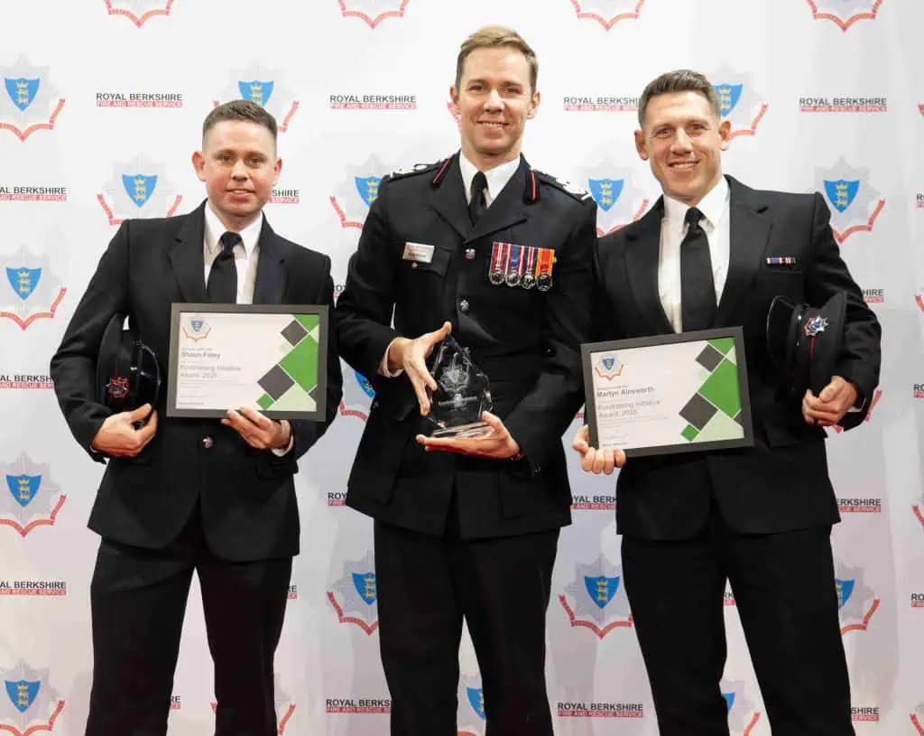 Three people with a trophy and certificates