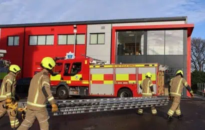 firefighters carrying a ladder during a drill