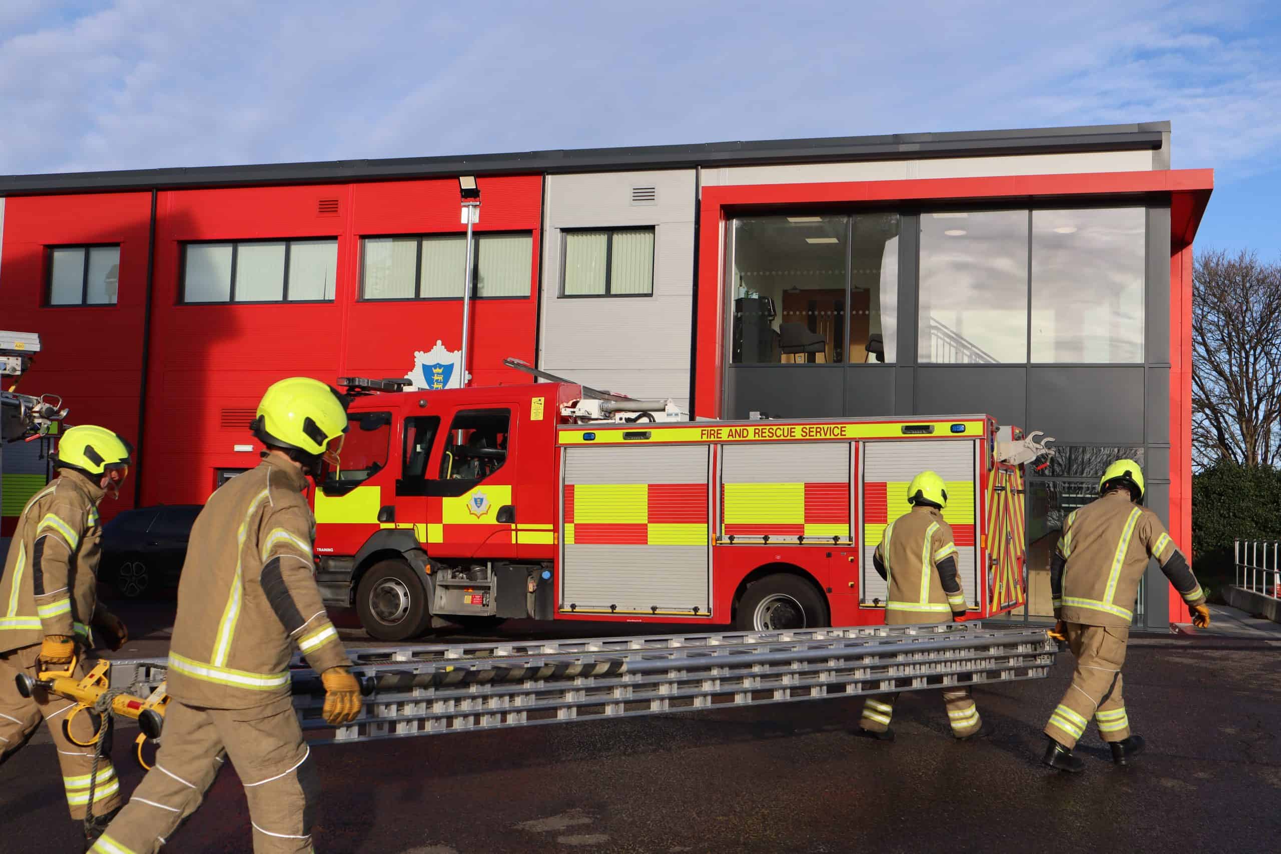 firefighters carrying a ladder during on-call firefighter assessment.