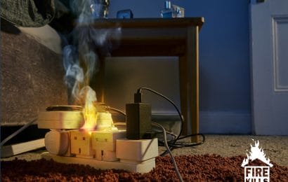 An extension cable overloaded with plugs. The plugs are on fire and producing smoke.