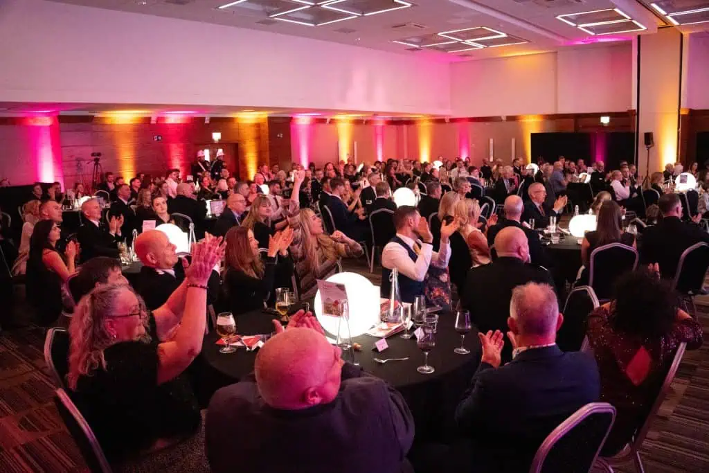 People at the Awards Ceremony celebrate with their hands in the air.
